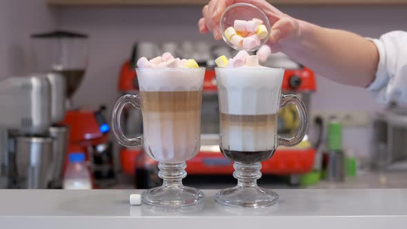 Barista Putting Marshmallows on Two Milkshakes at the Counter of a Restaurant