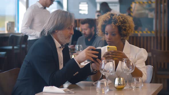 Portrait of Diverse Business Partners on Lunch in Cafe Using Smartphone and Talking