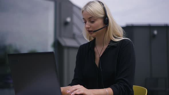 Medium Shot Slim Beautiful Smiling Young Woman in Headphones Talking Texting on Laptop Keyboard