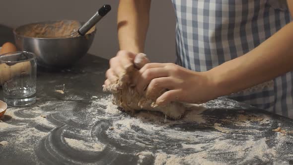 Closeup Women's Young Hands Knead Dough From Grey Flour in the Evening