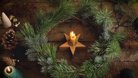 Candle burning in christmas wreath on rustic table