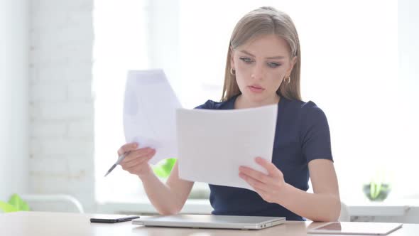 Woman Celebrating Success While Reading Documents in Office