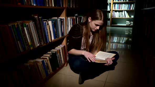 Student Sitting on the Floor and Reading a Book, Really Keen. Close Up