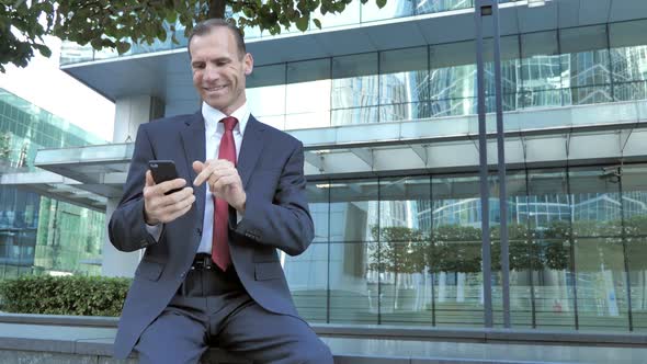 Middle Aged Man Excited for Success While Using Smartphone