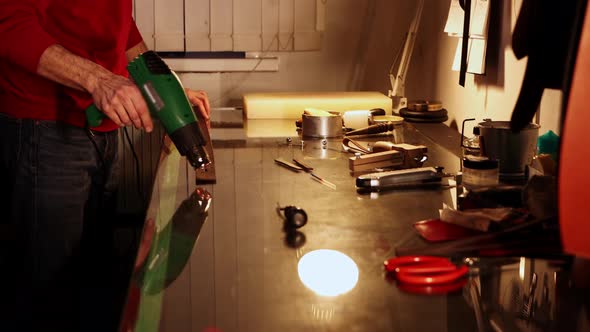 A Tailor Heats a Piece of Leather for a Belt in His Personal Workshop