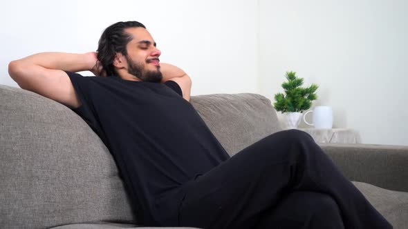 Tired Indian man comes and sits on sofa and starts thinking