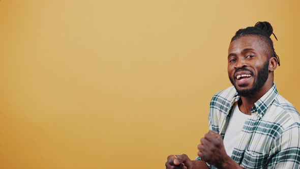 Young African American Male Smiling Clapping Hands and Dancing Walking Across Studio with Beige