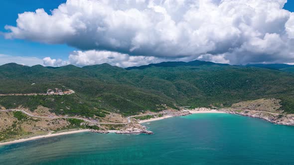 Rotating aerial hyper lapse showing water ripples reaching huge green cliffs, under moving cloudscap