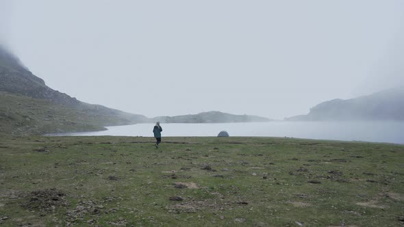 View of a Tourist Rushing Back to Her Tent By the Lake Ayous with Hovering Fog and Smoke Surrounded