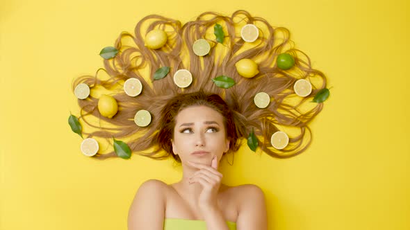girl lying with citrus fruits on long hair, woman thinking, thoughts in head, concept choice