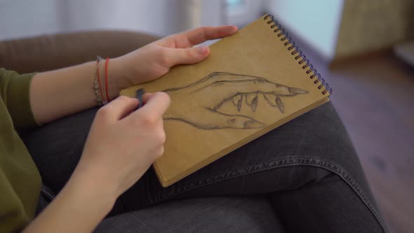 Woman Artist Draws in Sketchbook with a Pencil and Coal