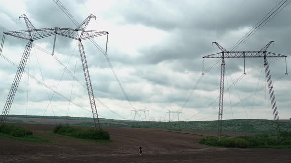 Girl Far In The Field. Large Electrical Structures.