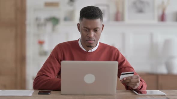 African Man making Online Payment Failure on Laptop in Office