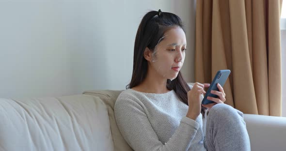 Woman use paper mask with cellphone at home