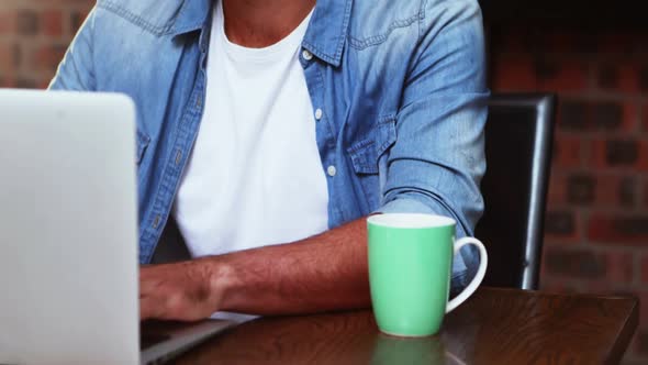 Man having coffee while working on laptop