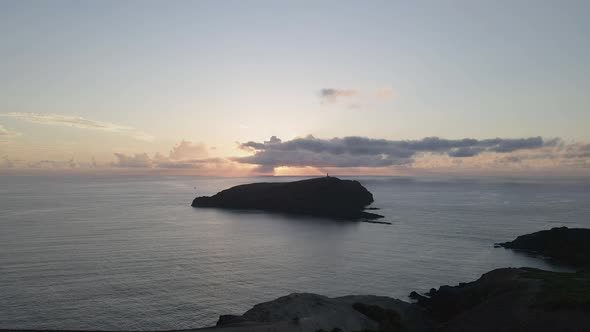 Aerial drone flying from Morenos viewpoint to Ilheu de Ferro island during sunset. Portugal