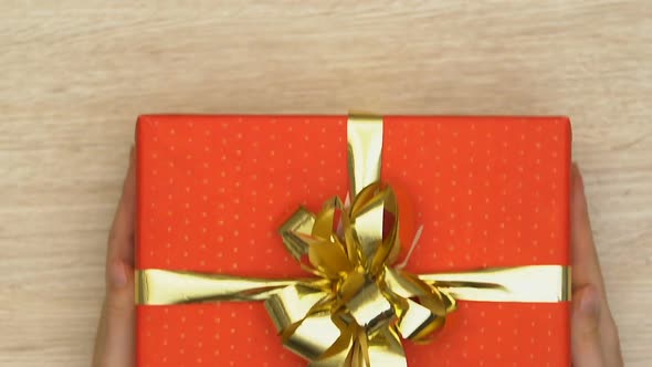 Hands Putting Gift Box on Table Present for Beloved One Holiday Celebration