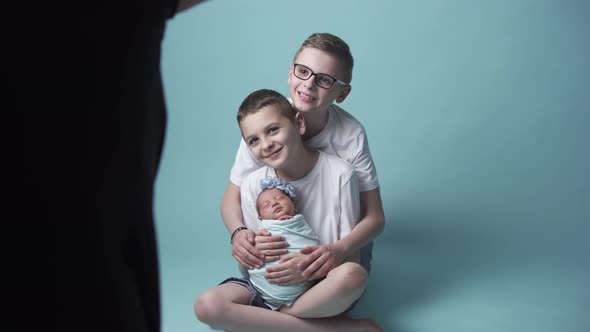 A Newborn Girl is Photographed Surrounded By Her Older Brothers