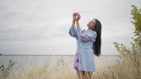 Adorable Confident Carefree African American Girl Stands on the Background of a Lake or River