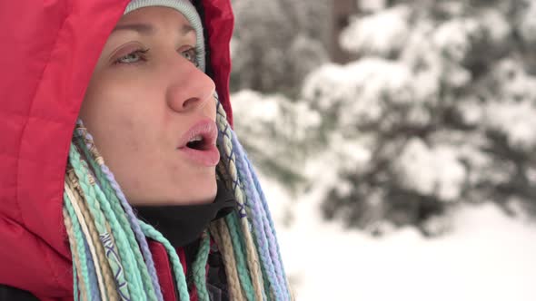 A Woman Exhales Steam in the Frosty Air in Winter