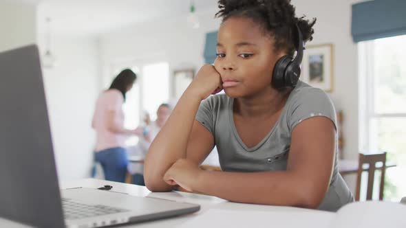 Happy african american girl using laptop for online lesson at home