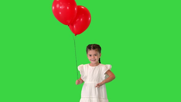 Adorable Little Girl Holds Tightly To a Large Bunch of Helium Balloons Walking on a Green Screen