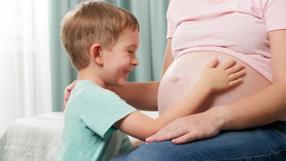 Smiling Happy Little Boy Tickling and Having Fun with Big Pregnant Belly of His Mother