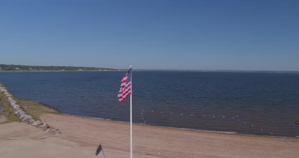 Aerial Pan Around of American Flag at Memorial Park and Boats Anchored at Harbor