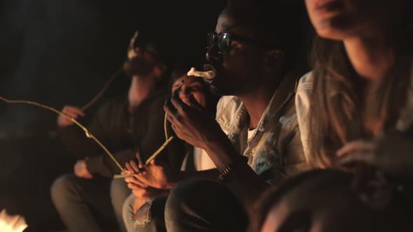 Young People Eating Marshmallows by Campfire at Night