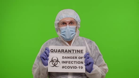 Doctor in PPE Suit Showing Warning Text Slogan on Paper  Quarantine Danger Of Infection Covid19