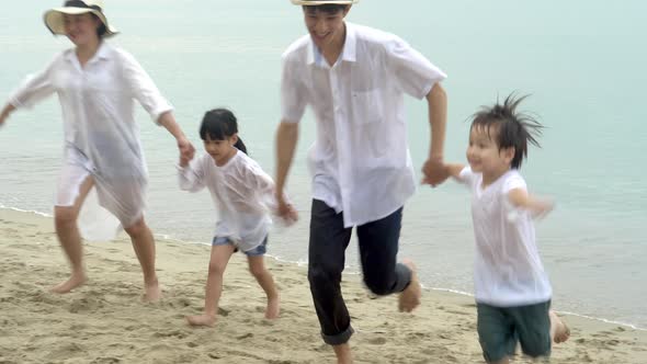 Happy asian family running for relax on vacation together in the beach.