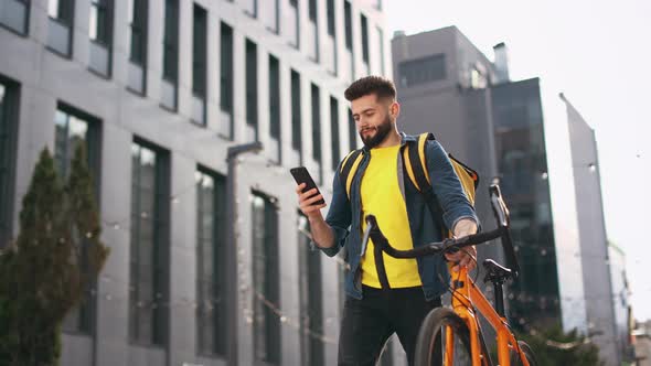 The Food Delivery Guy is Going and Looking at the Smartphone