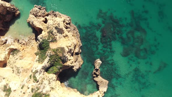 Bird's-eye view of cliffs and crystal clear ocean on a calm day, Lagos, Algarve, Portugal