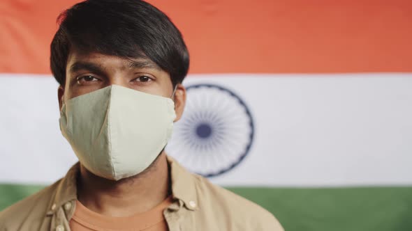 Indian Man in Protective Mask Posing against National Flag