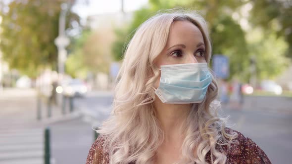 A Middleaged Caucasian Woman in a Face Mask Looks Around in an Urban Area  Closeup