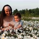 A Young Mother and Her Son Reading a Book Sitting on a Flower Lawn in the Park - VideoHive Item for Sale