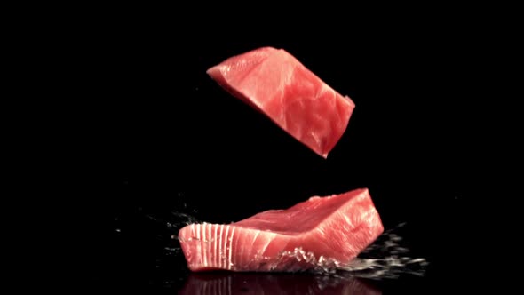 Super Slow Motion Two Raw Tuna Steaks Fall on the Table with Splashes of Water