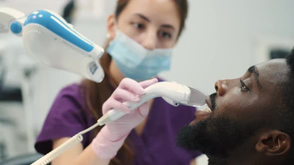 Side Shot of a Young Man Whitening His Teeth at the Dentist