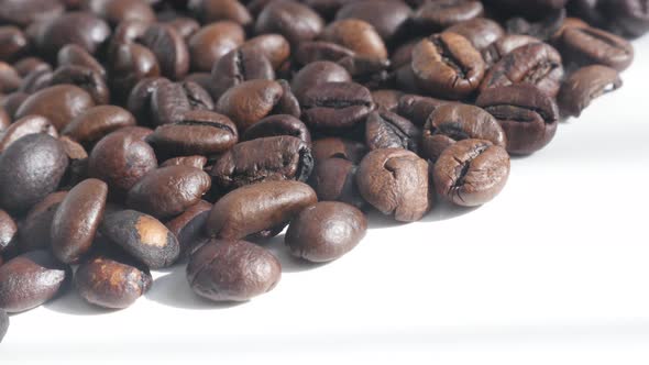 Dark roasted coffee beans  on white 4K slow pan video