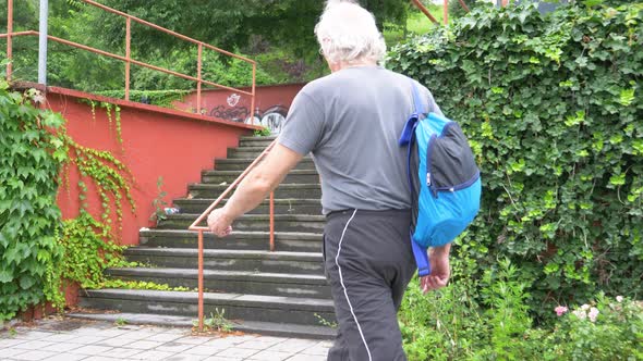 Senior athletic man with backpack climbing stairs