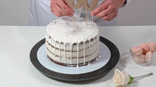 Beautiful Birthday Cake Decorated with Macarons and a Rose Being Proudly Presented By a Female Baker