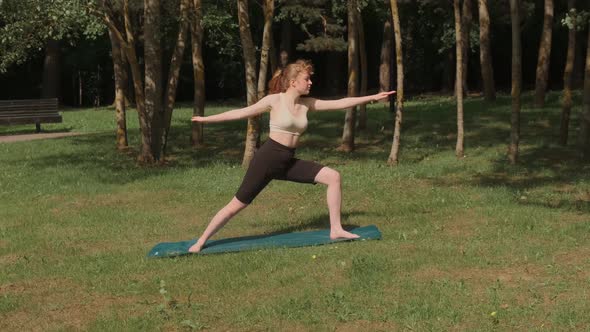 A Young Girl is Doing Yoga in a Public Park in the Fresh Air