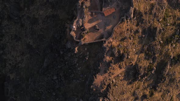 Aerial top-down forward over Monsanto ruins at sunrise. Portugal