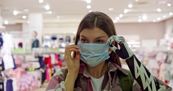 Closeup of a Customer in a Shopping Center Who Removes a Protective Mask with the Help of a Bionic