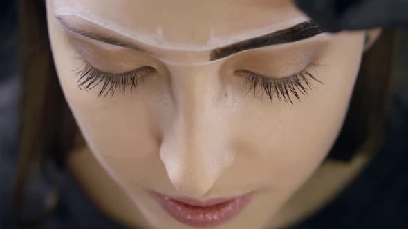 Above Shot of a Stylist Making Eyebrow Correction for Lovely Woman at Beauty Salon