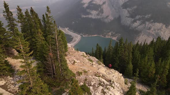 Aerial drone video of a man with red T-shirt and a bag hiking and trekking through Rocky Mountains d