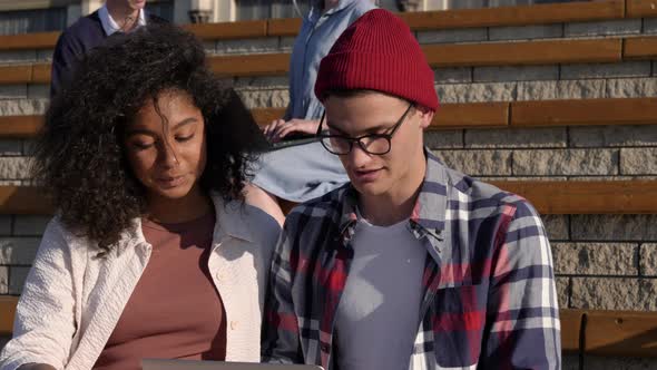 Mixed Race Students Couple Spending Time Together Doing Something on a Laptop.