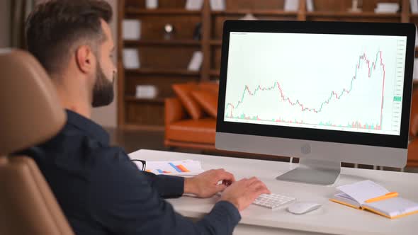 Focused and Concerned Man in Smart Casual Shirt Looking at Laptop Screen