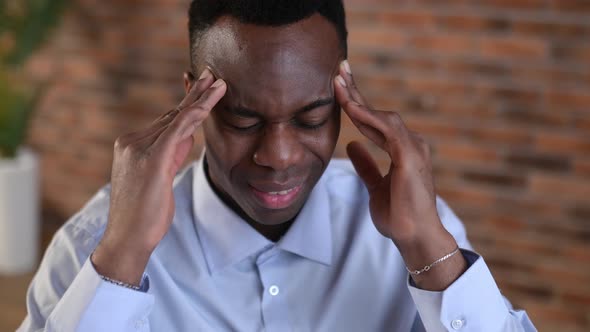 Closeup of an Exhausted African American Man Experiencing Headache Migraine Overwork From Working at