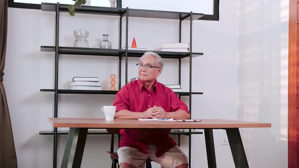 Senior Asian man sitting over office desk relaxing.